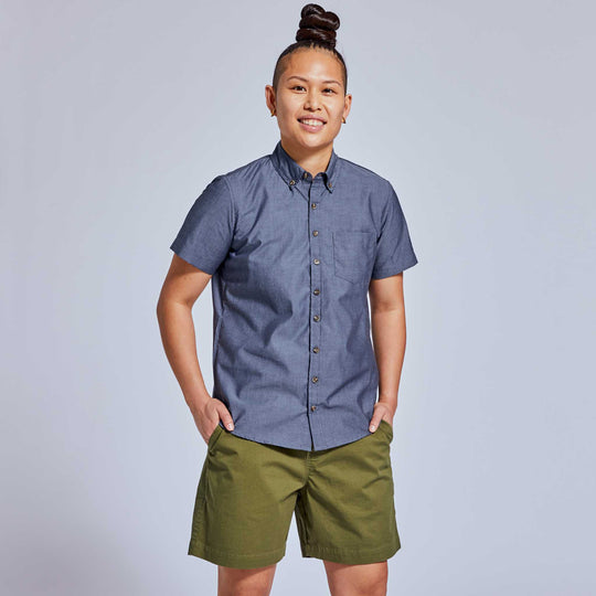 Moss green shorts with slate blue chambray shirt on non-binary model
