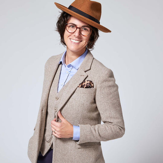 Androgynous person modeling the taupe tweed blazer and vest combination over a light blue dress shirt. All these pieces are by Kirrin Finch.