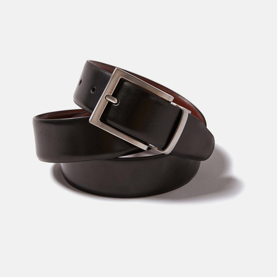 Reversible leather belt by Kirrin Finch coiled upon itself. Showing Black leather side and zinc belt buckle.