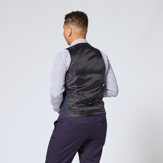 Model showing black contrast back of dark navy tweed herringbone vest and navy grid dress shirt by Kirrin Finch