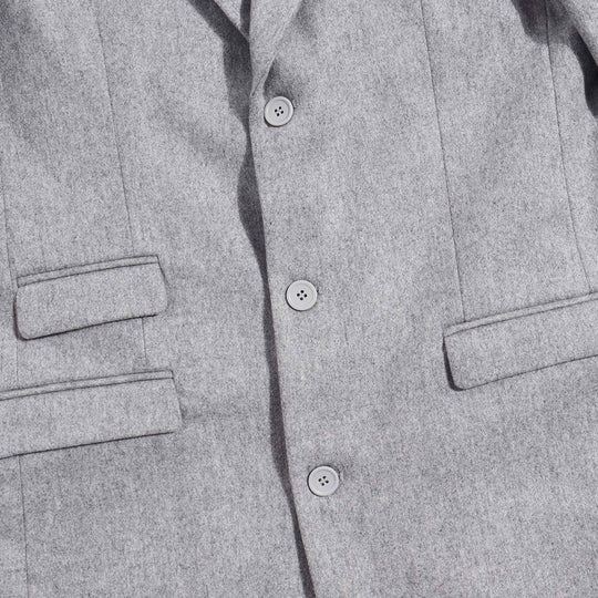 Gray over coat details, two pockets on left side of garment, one pocket on the right. Three Gray buttons fastened.