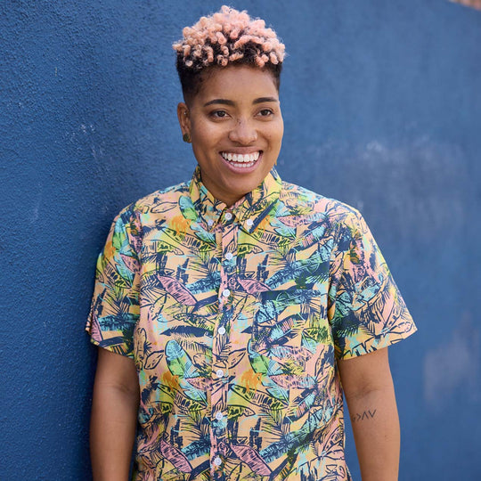 Smiling model wearing Piper multi-colored shirt against a blue wall