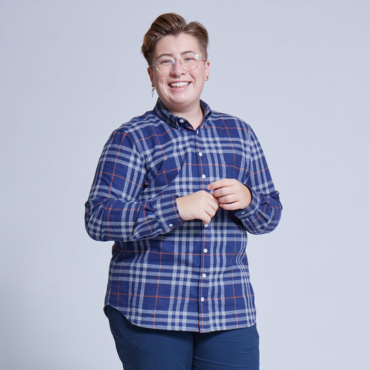 Androgynous model wearing Navy plaid button down shirt on neutral background