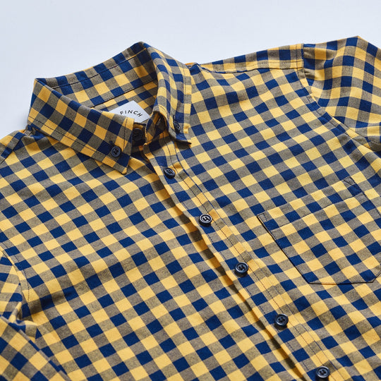 Kirrin Finch's yellow and navy buffalo check shirt laid flat on a neutral background