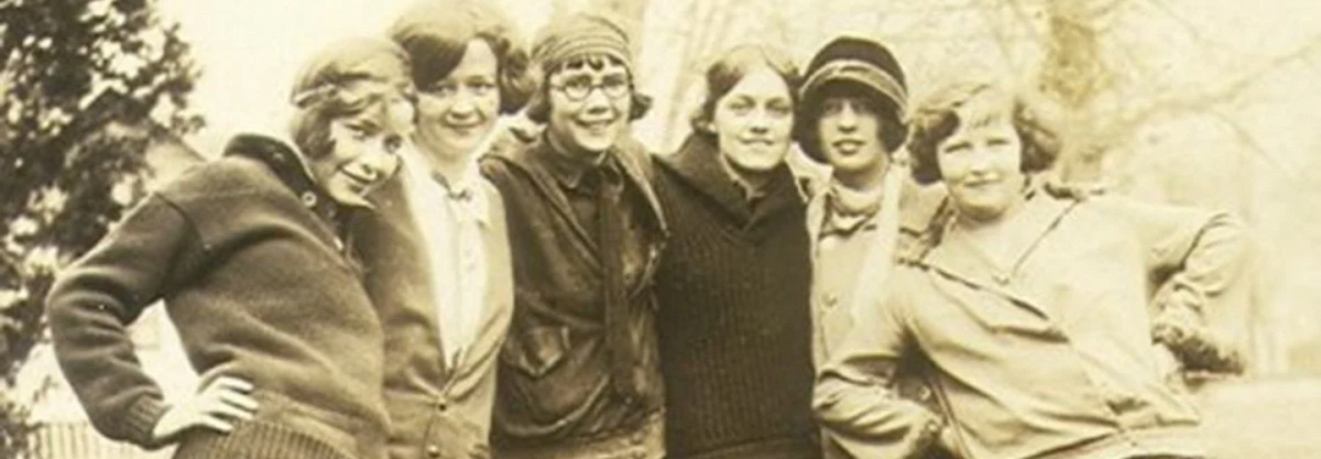 Six young women in men's sweaters, breeches and knit caps posing outdoors in the early 1920s