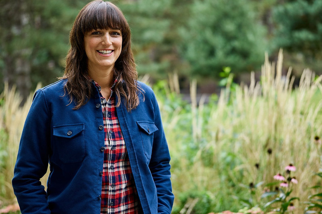 Model wearing a navy shirt jacket standing in a field with tall grass.