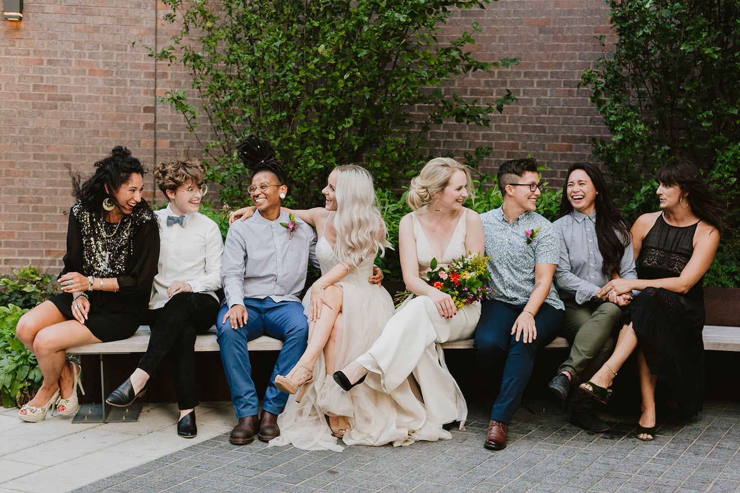 Wedding party siting on a bench.
