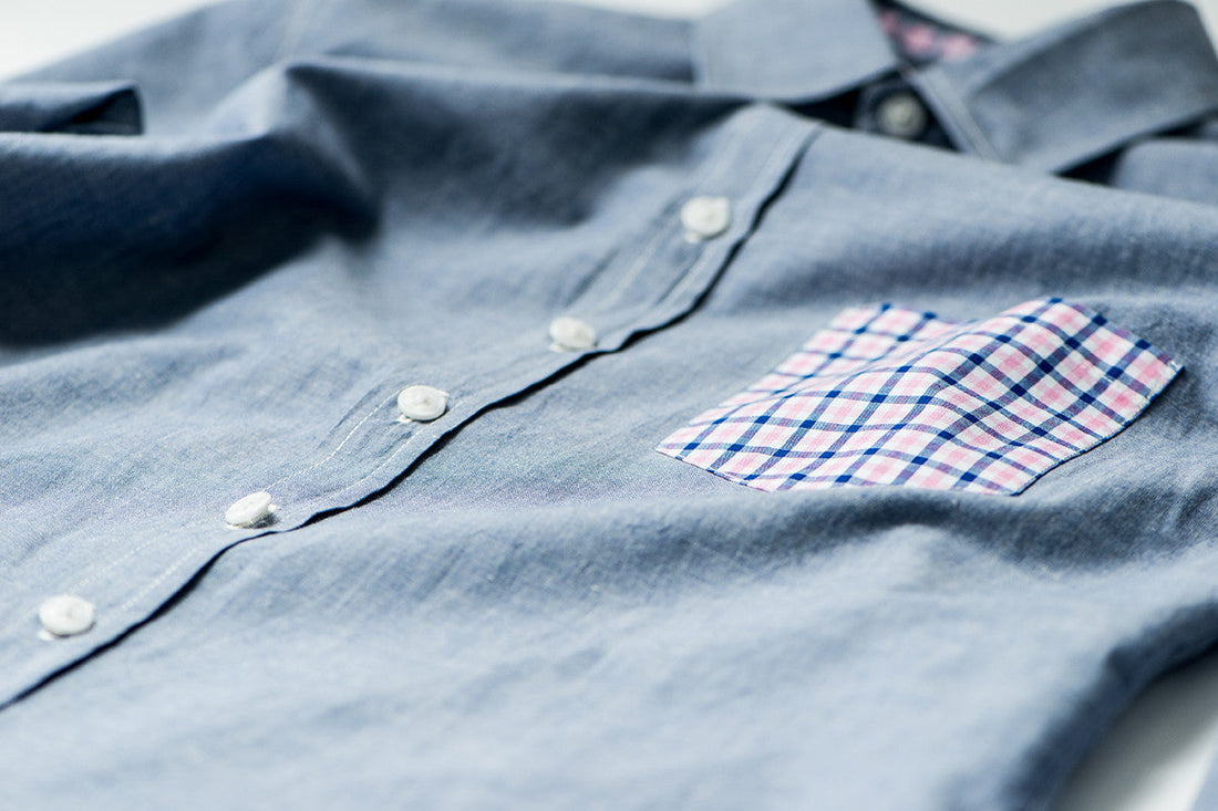 Blue button down shirt with checkered front pocket.