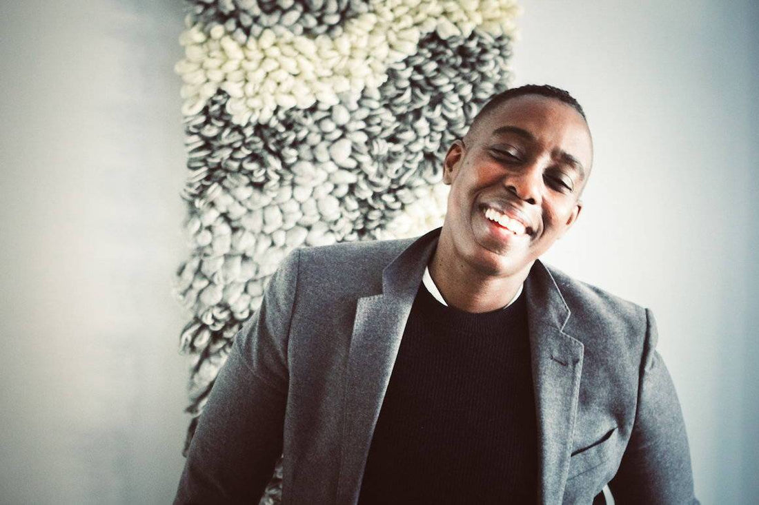 Smiling person in a gray blazer and black top, an androgynous professional style look for the office