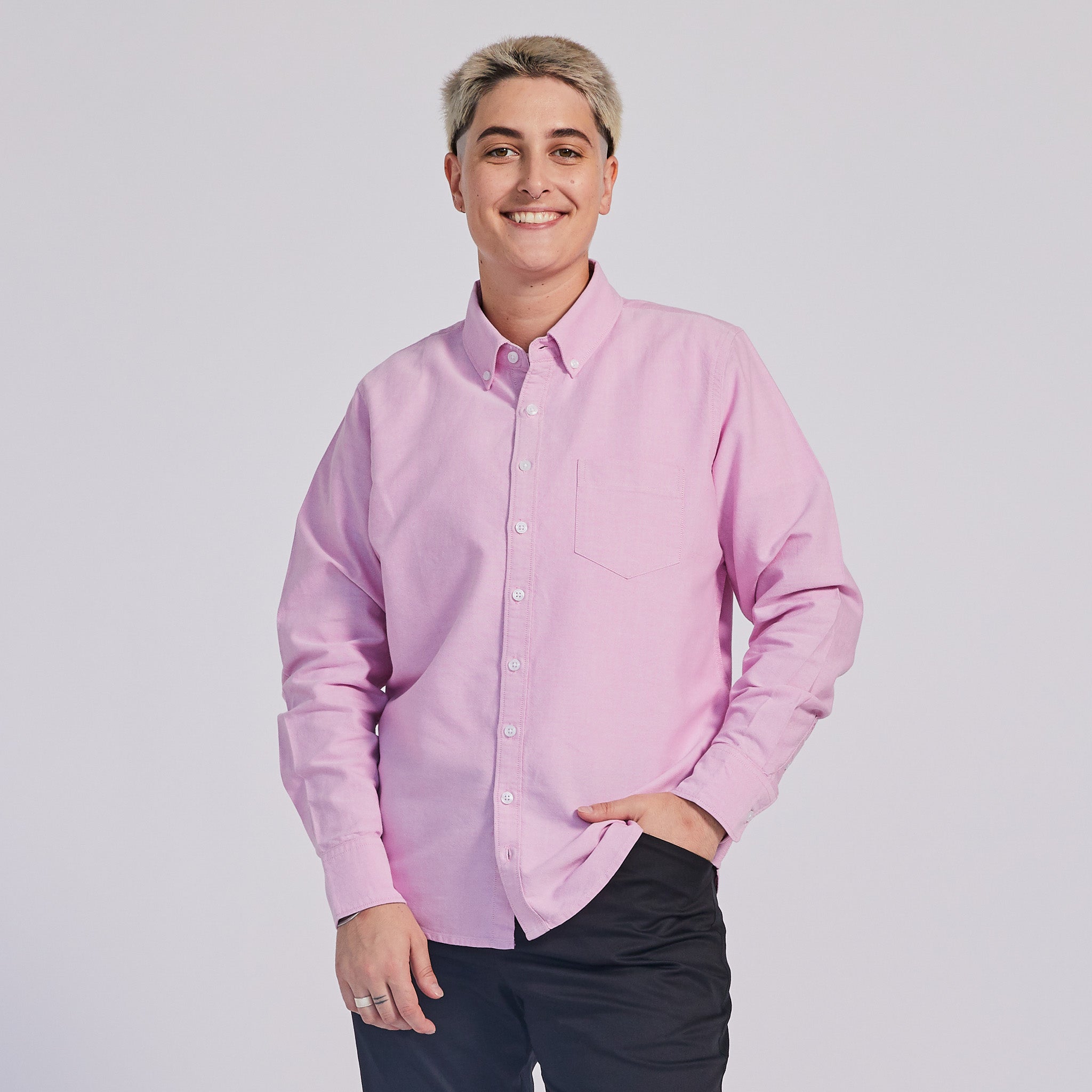 non-binary model in pink button down Oxford shirt