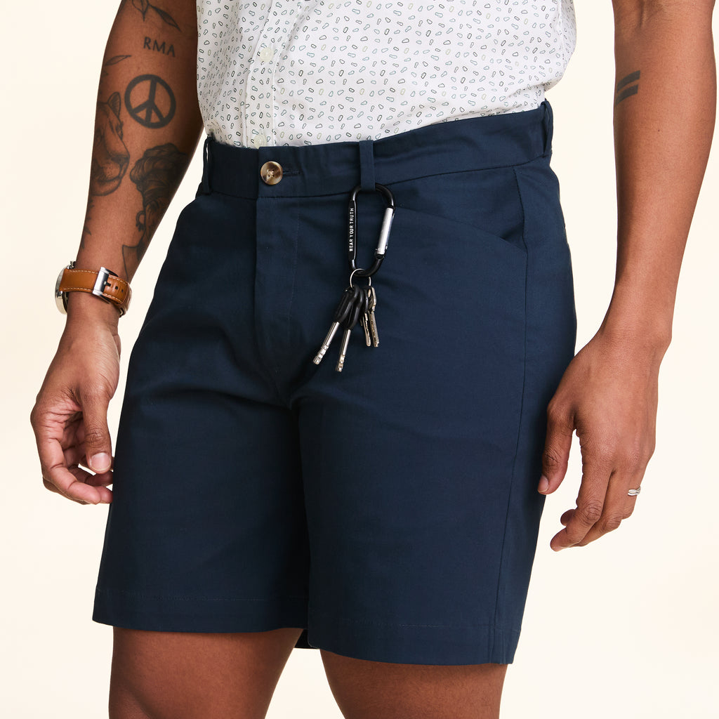 A person wearing navy blue shorts with a carabiner attached to the waistband.