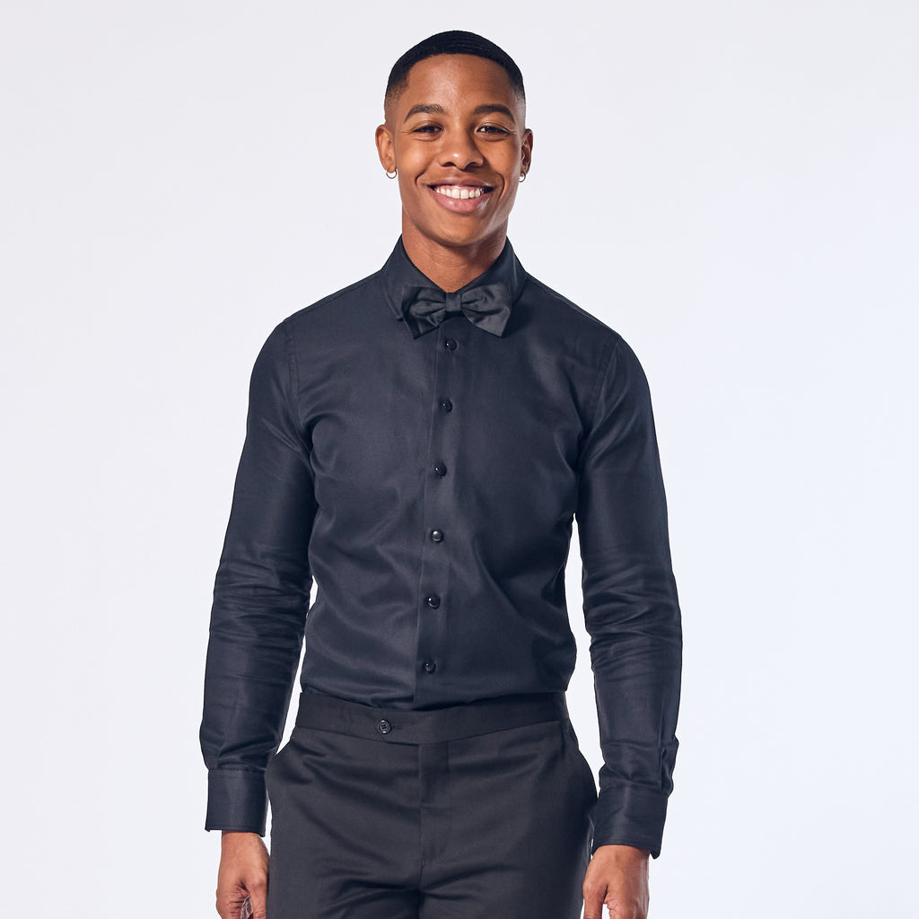 A person wearing a Jet Black Tuxedo Shirt with long sleeves, button-up front, and a collar.