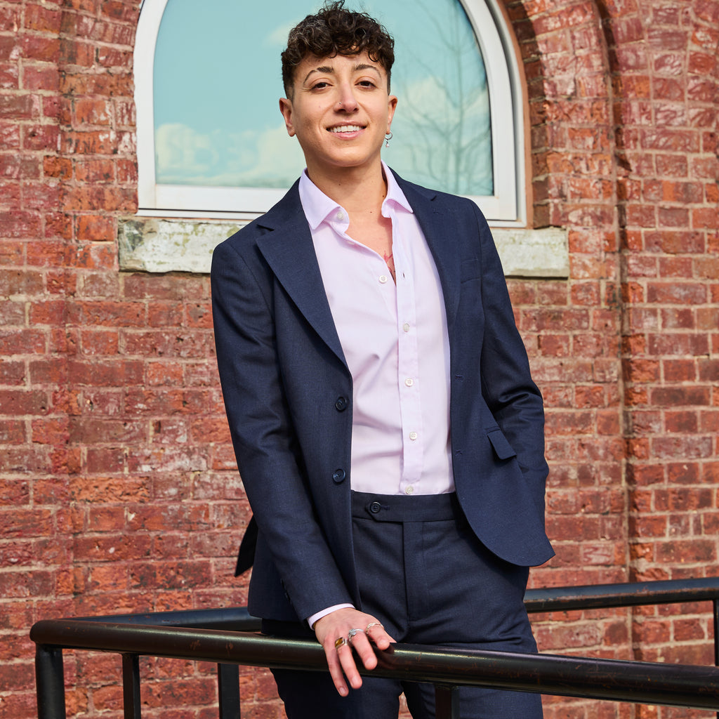 Model wearing The Scout Ink Blue Suit Blazer made by Kirrin Finch standing against a brick wall.