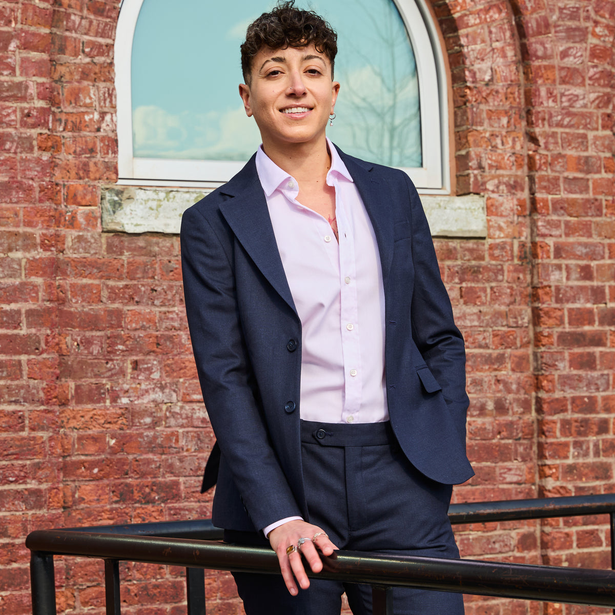 Model wearing The Scout Ink Blue Suit Blazer made by Kirrin Finch standing against a brick wall.