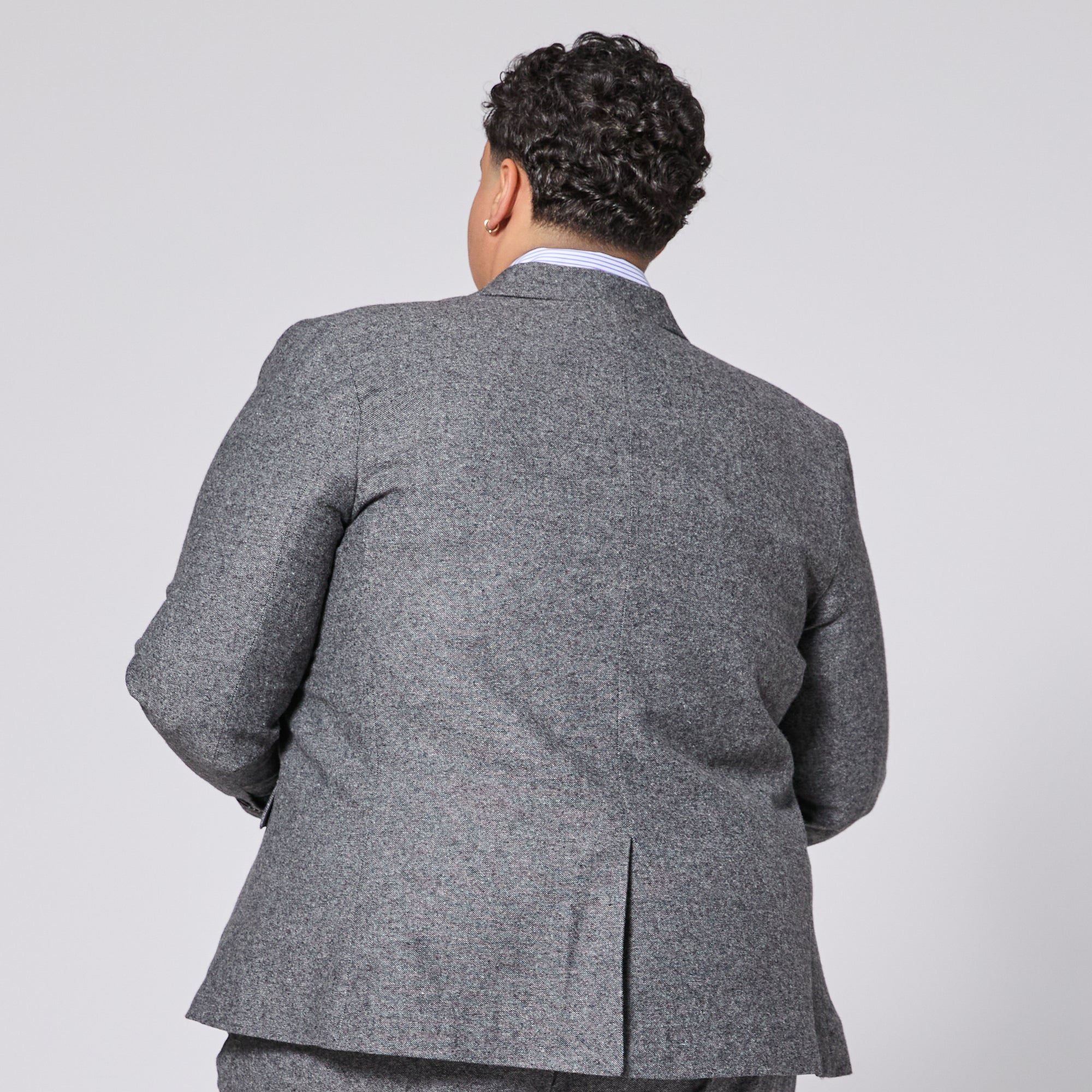 Person wearing a gray suit jacket on a plain background