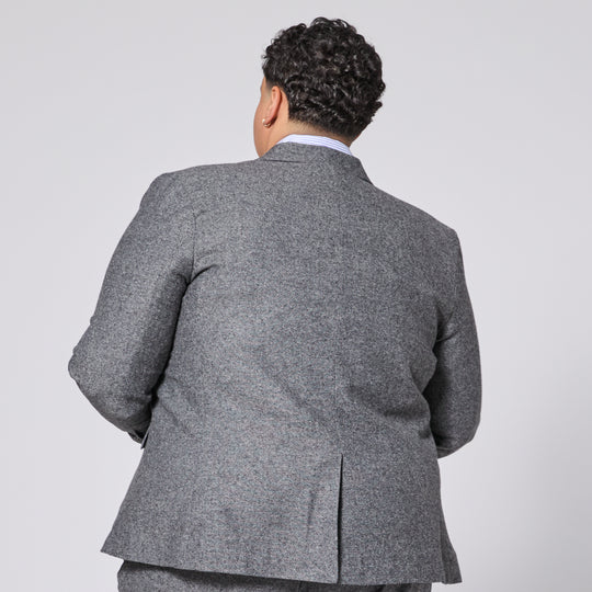 Person wearing a gray suit jacket on a plain background