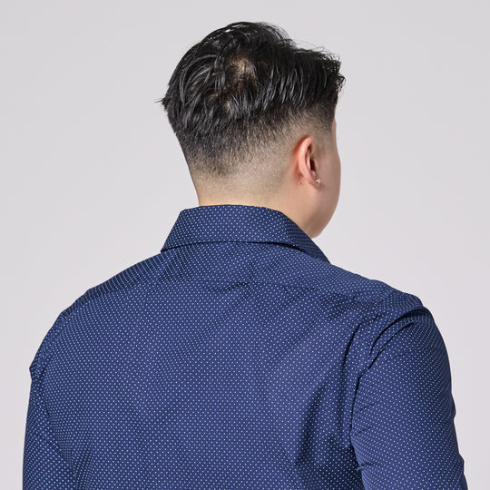 Person wearing a blue patterned shirt from behind on a plain background