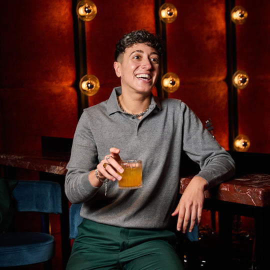 Model wearing Gray long sleeve polo sweater at a bar.