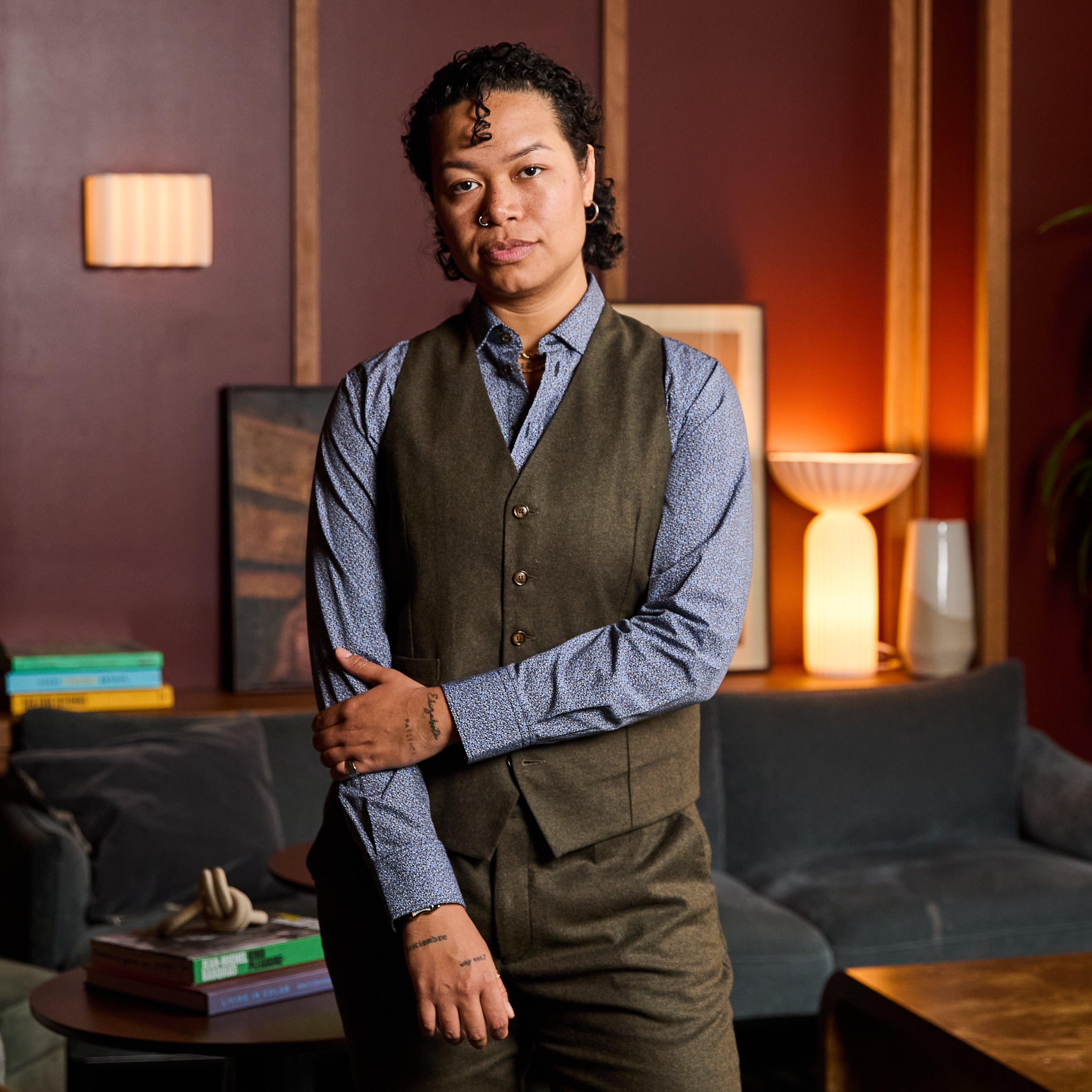 Model wearing The Finch Heather Olive Flannel Vest made by Kirrin Finch in a cozy room.