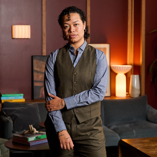 Model wearing The Finch Heather Olive Flannel Vest made by Kirrin Finch in a cozy room.