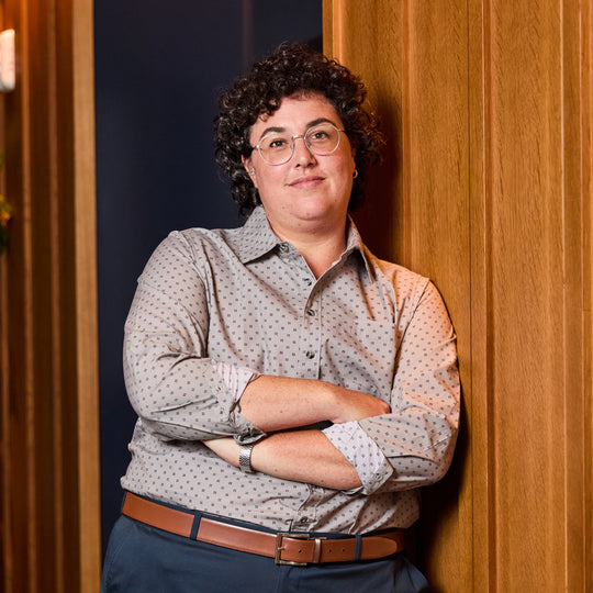 Model wearing Storm KF Emblem Point Collar Shirt made by Kirrin Finch against a wooden panel background