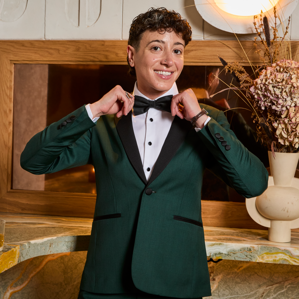 Androgynous model adjusting bow tie in a formal setting. Color: Emerald