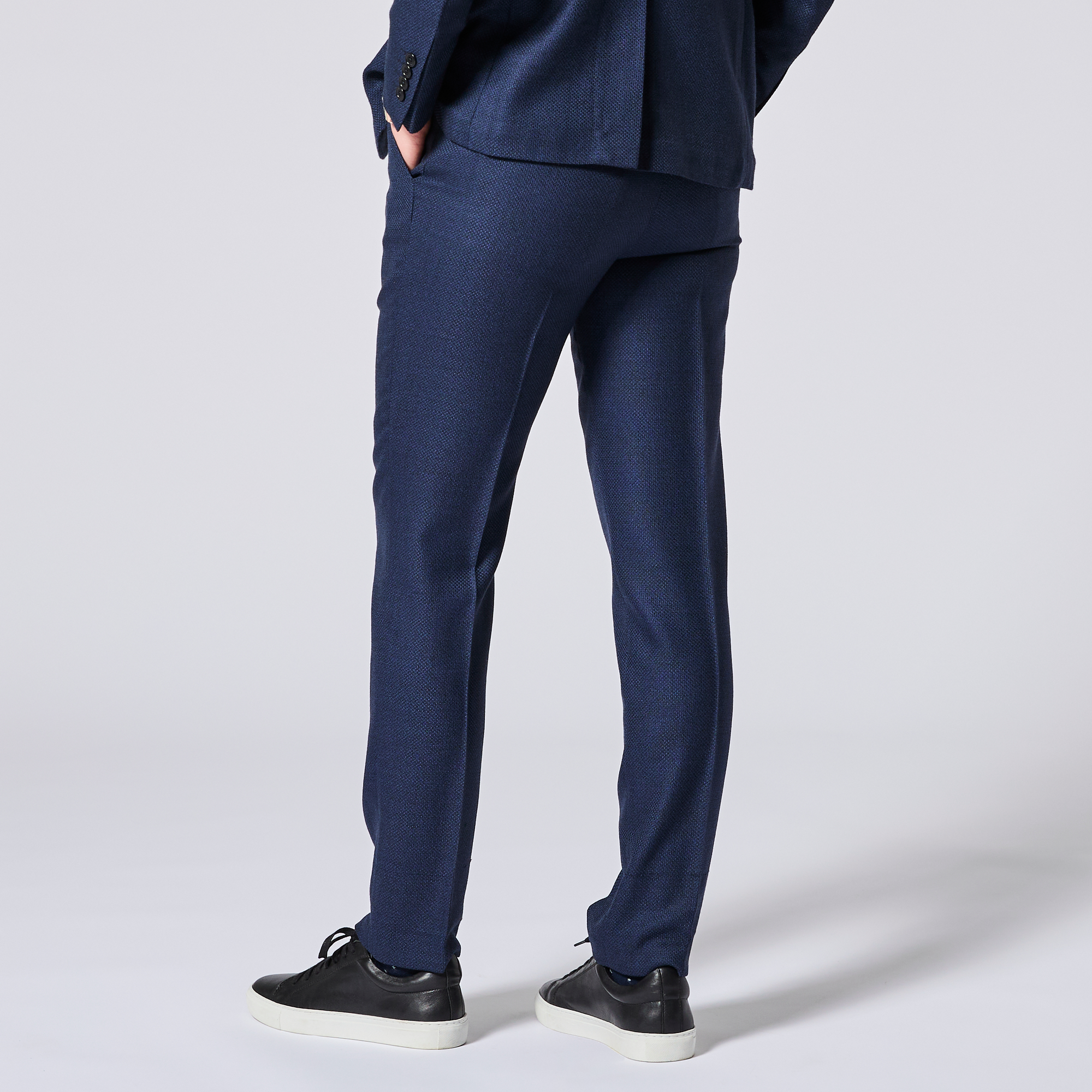 Textured navy blue suit pants worn by a person on a light gray background made by Kirrin Finch. Color: Navy Textured