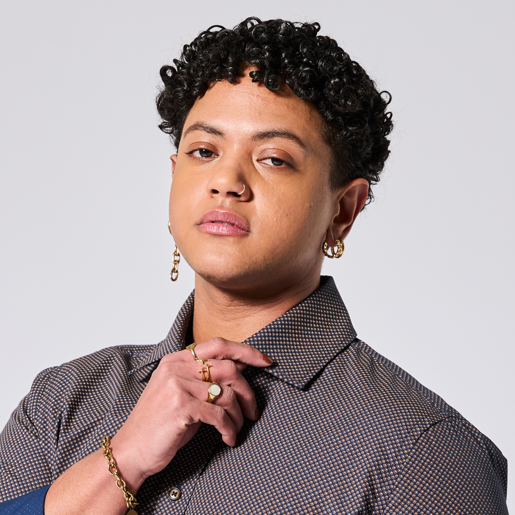Androgynous model wearing a patterned shirt with jewelry on a plain background. Color: Moroccan Tile