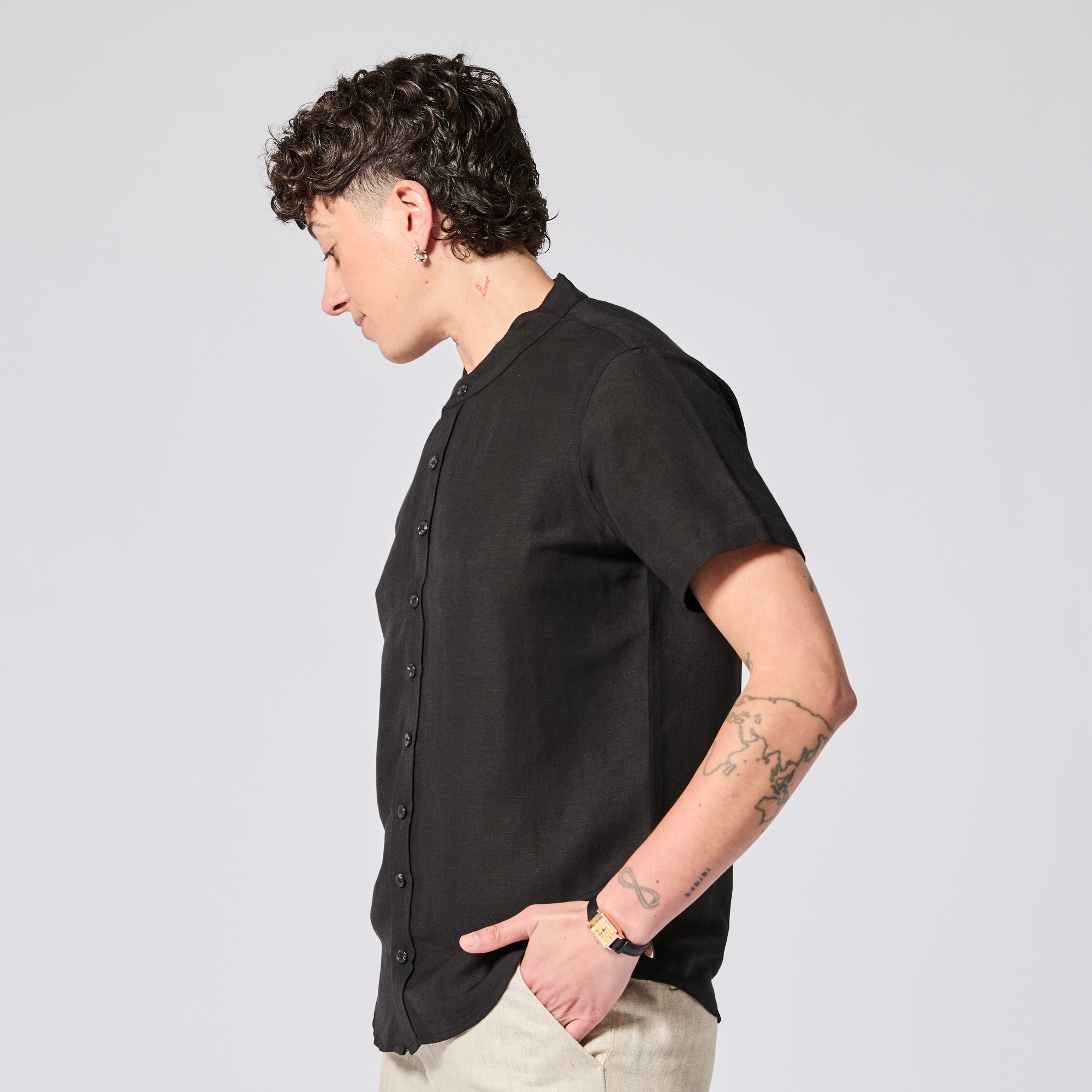 Model wearing a black short-sleeve shirt on a light gray background made by Kirrin Finch. Color: Black