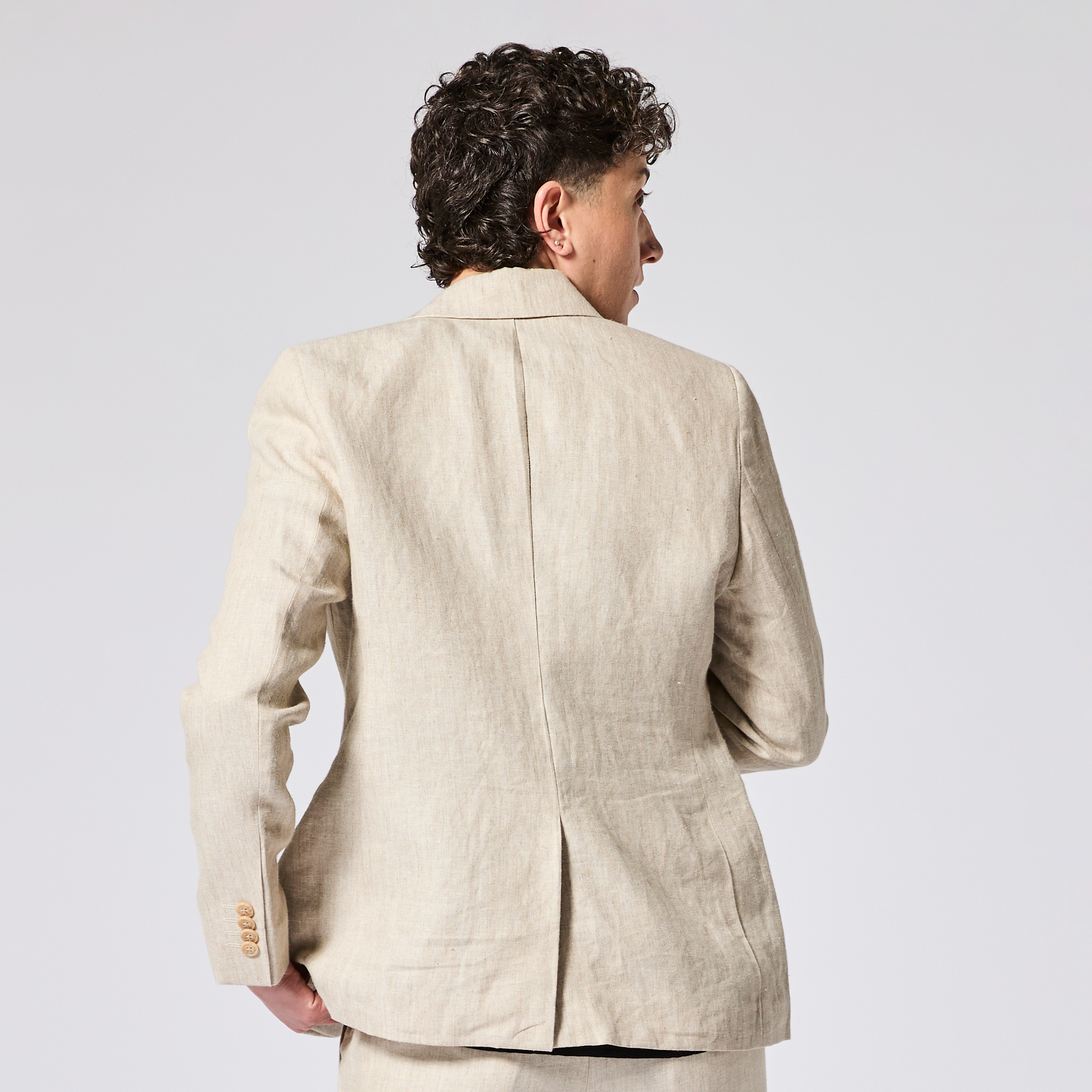 Person wearing a beige linen blazer on a plain background. Color: Khaki Herringbone