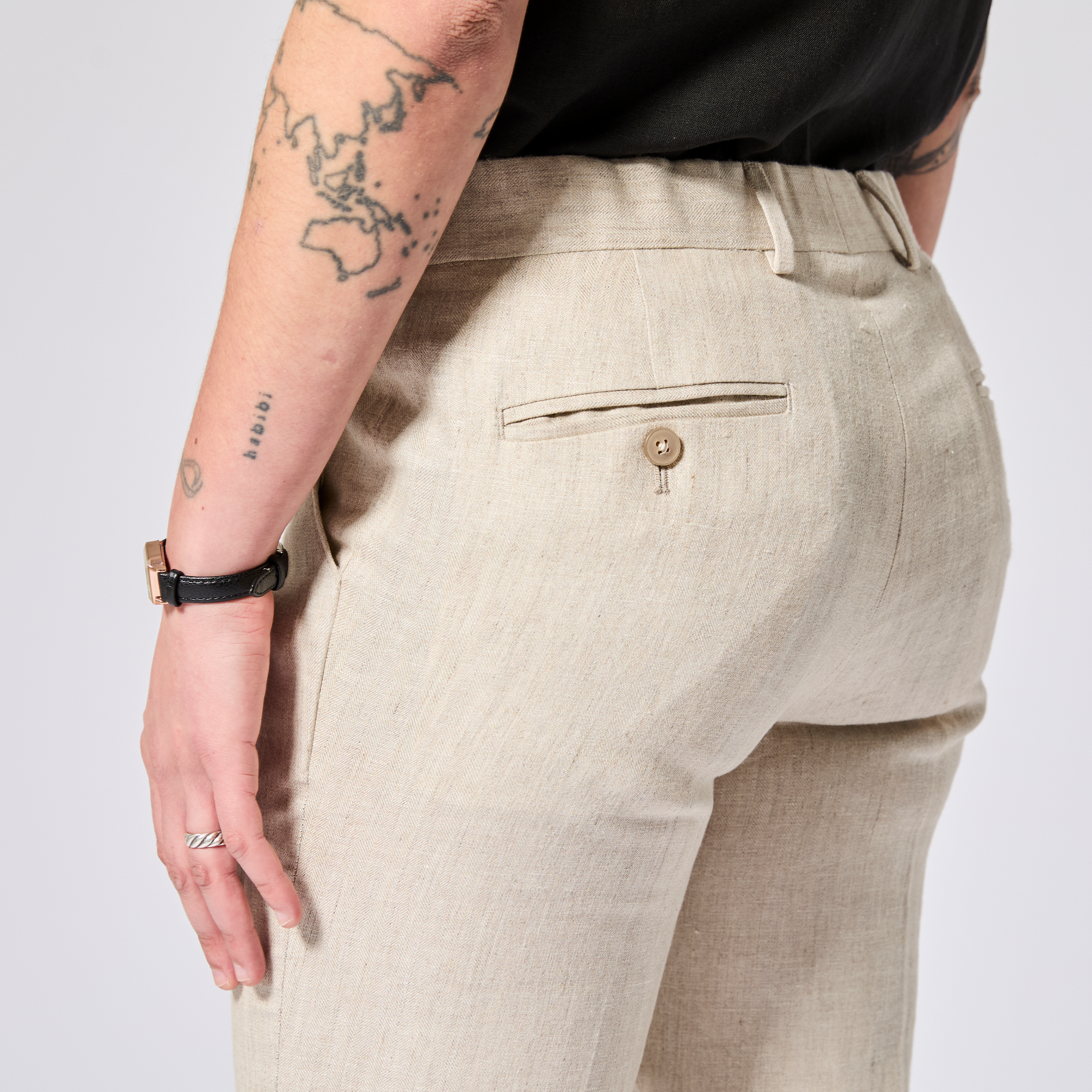 Beige pants worn by a person on a plain background. Color: Khaki Herringbone