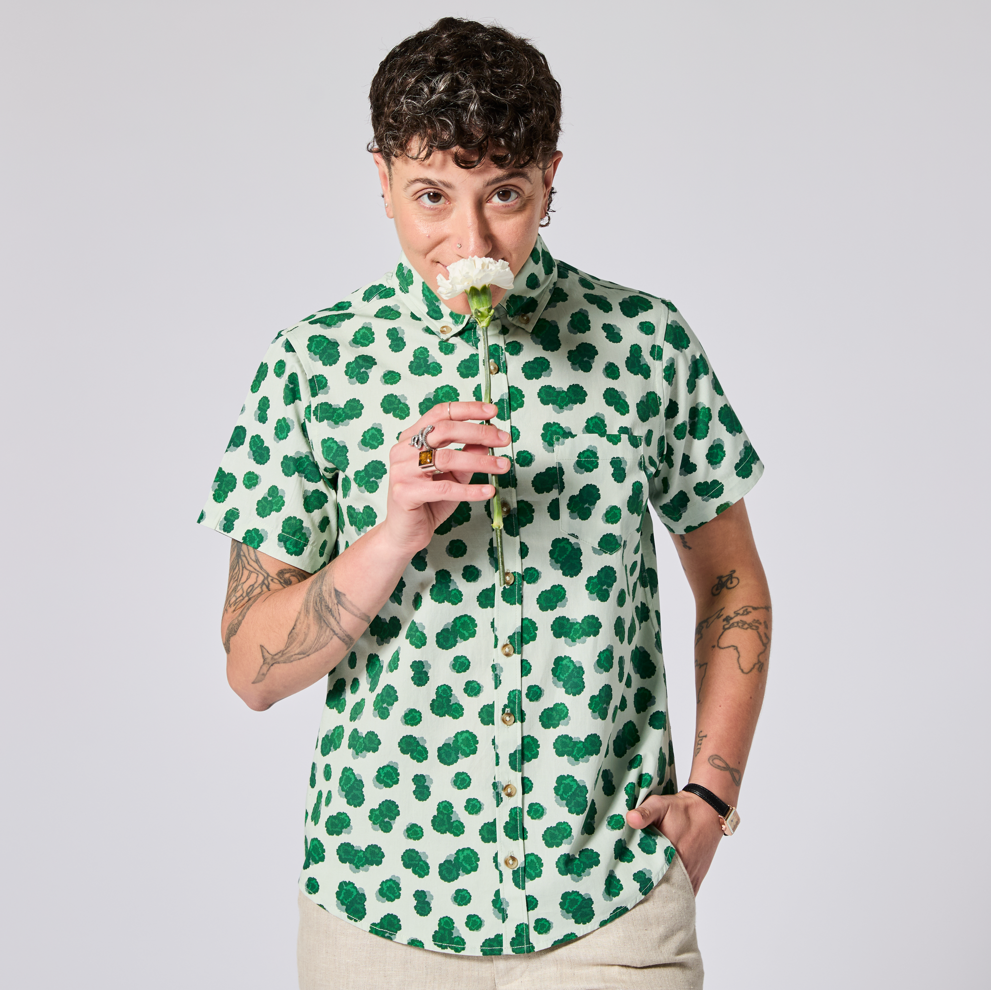 Model wearing the green carnation Ray shirt holding a flower against a plain background. Color: Green Carnation