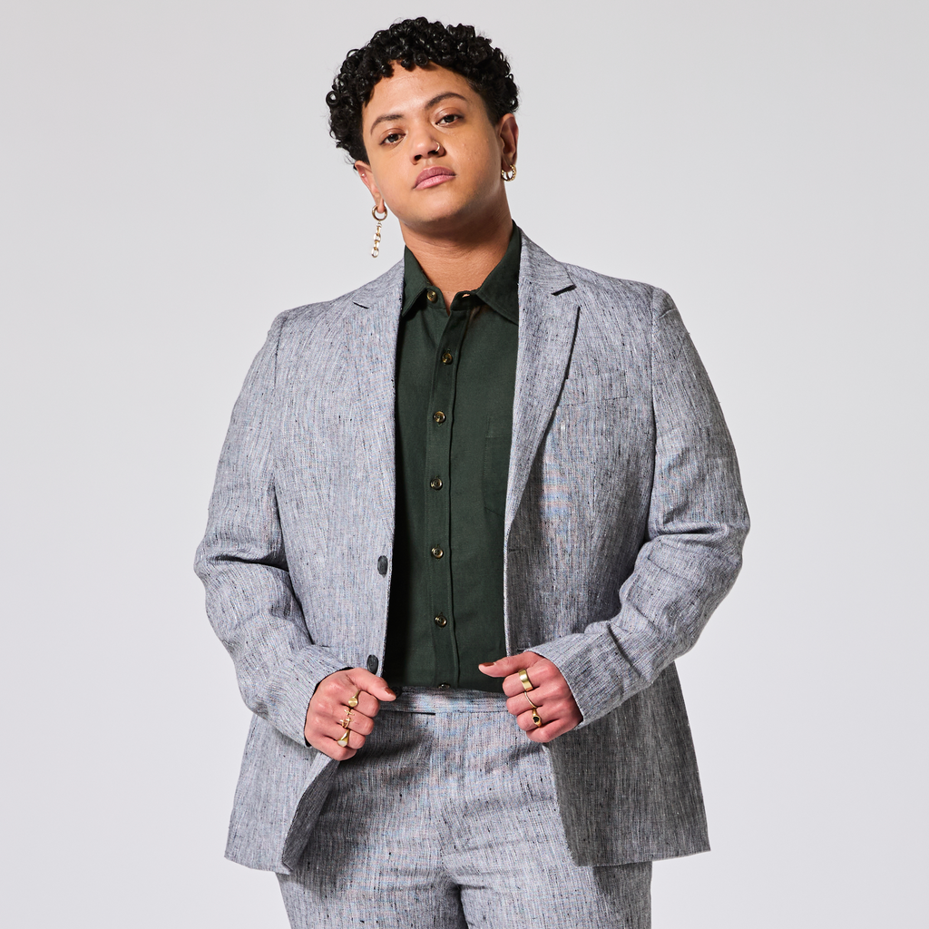 Person wearing a gray suit and green shirt against a plain background. Color: Graphite