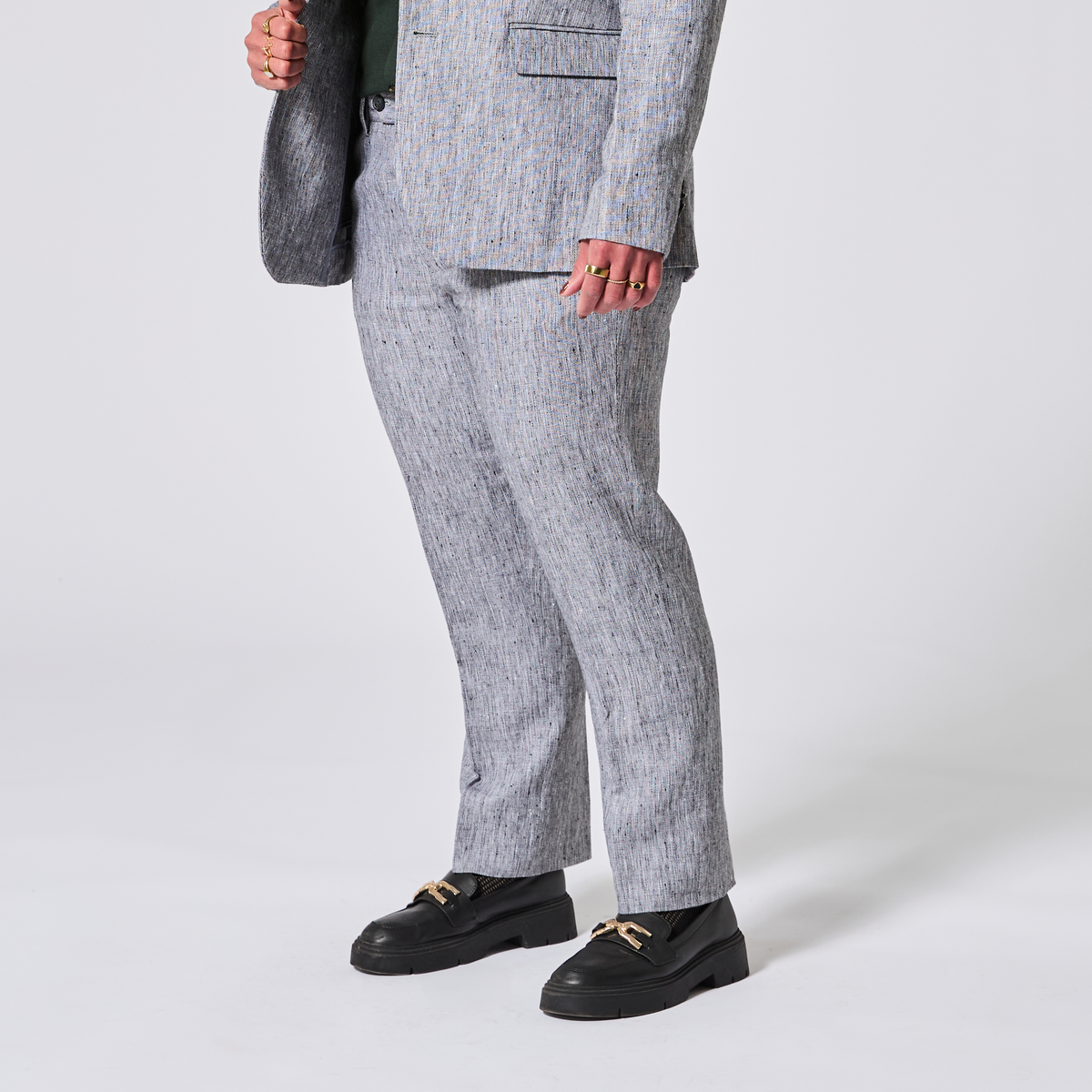 Person wearing a gray suit with with matching pants on a white background. Color: Graphite