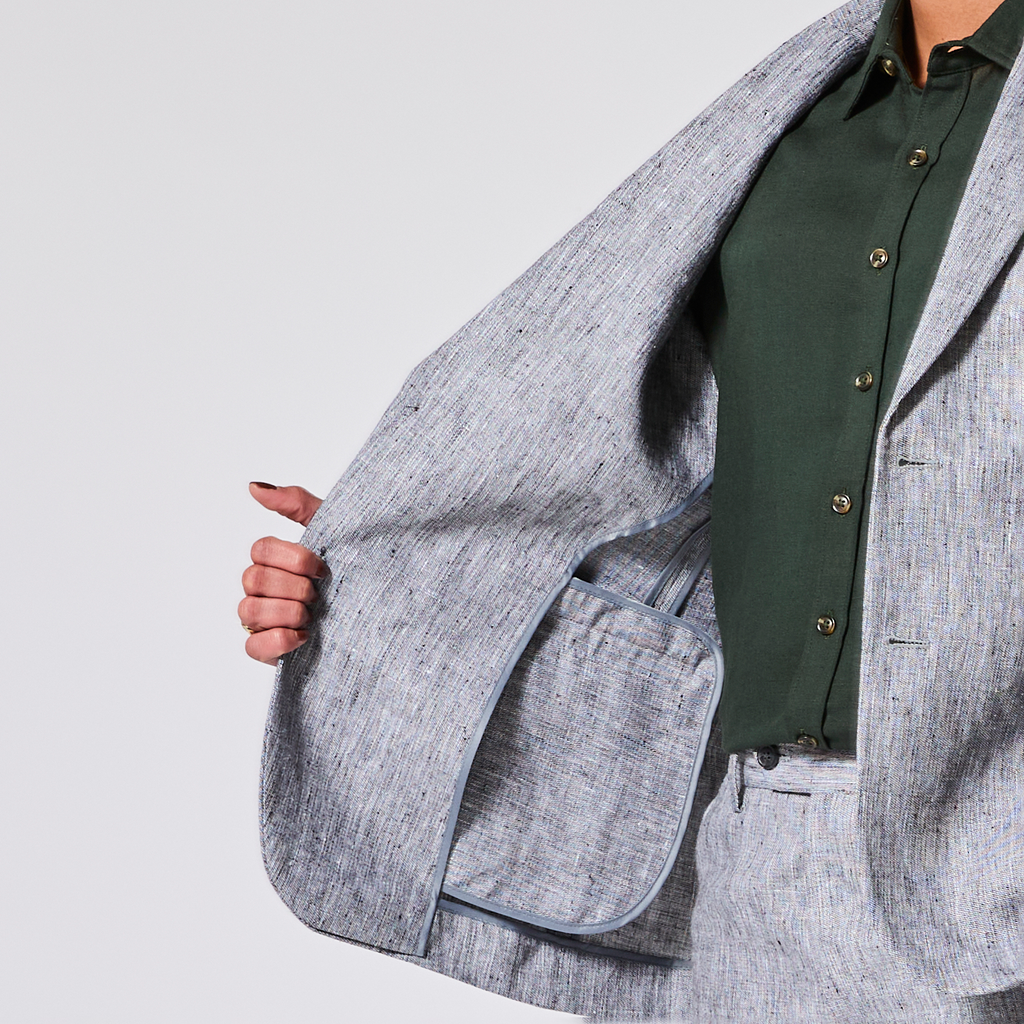 Person wearing a gray jacket over a green shirt on a light gray background. Color: Graphite