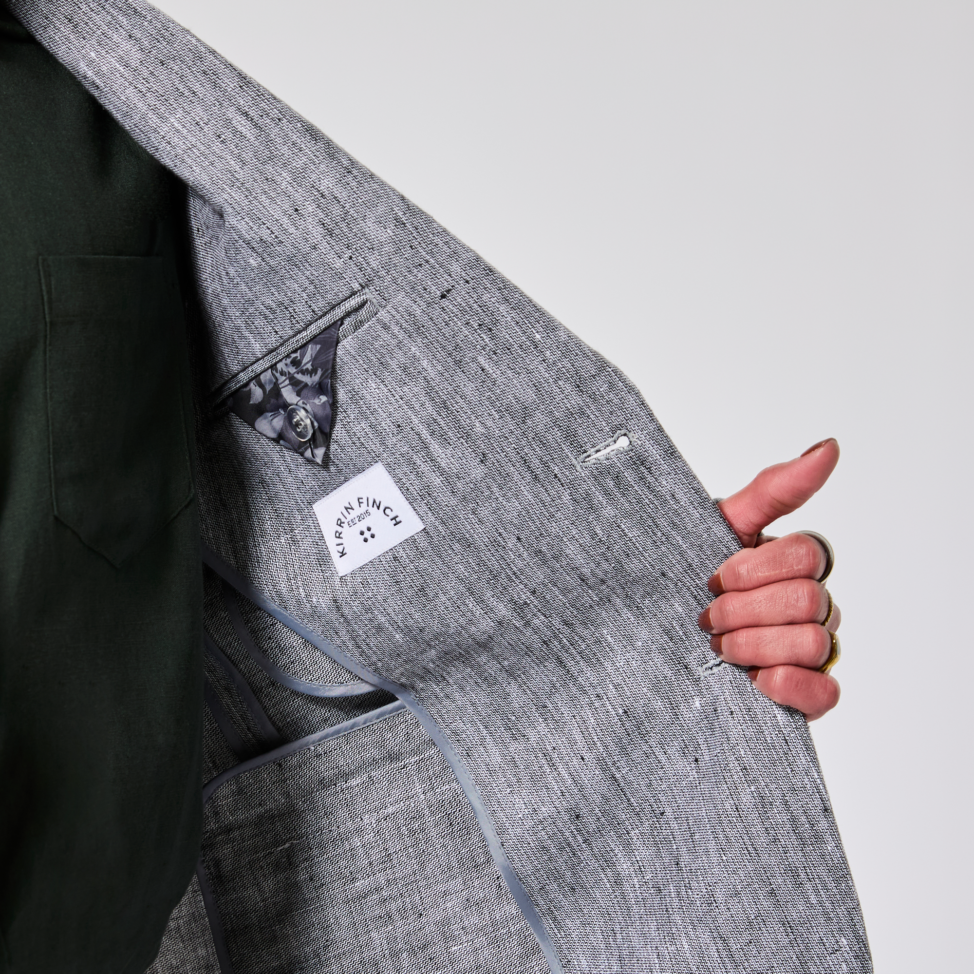 Gray textured bag with a brand logo held by a hand against a light gray background. Color: Graphite