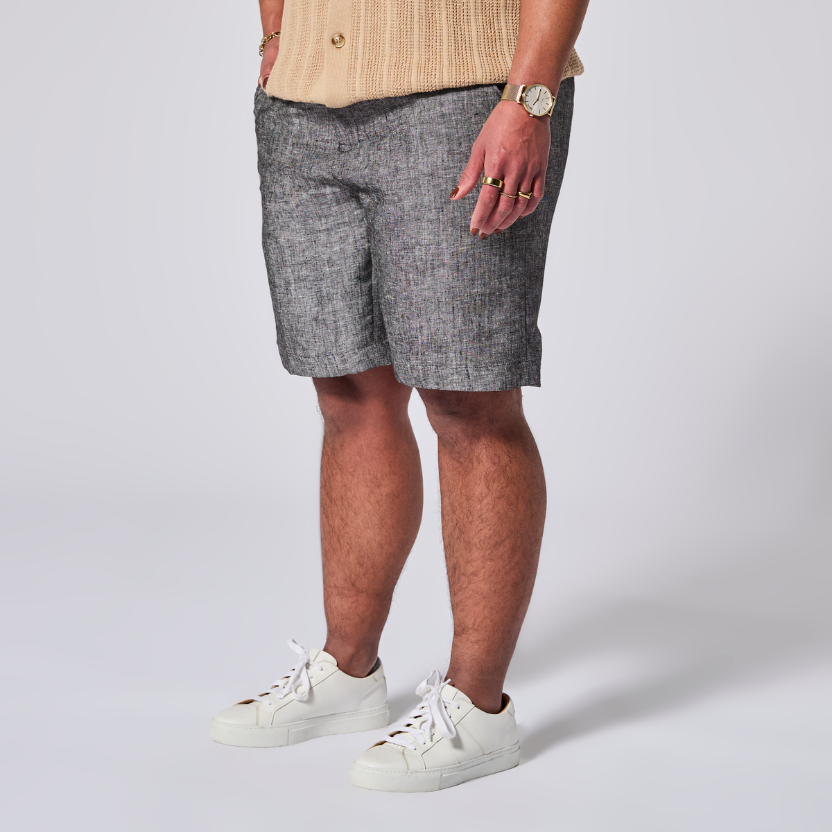 Person wearing gray shorts and white sneakers on a plain background. Color: Ash Gray