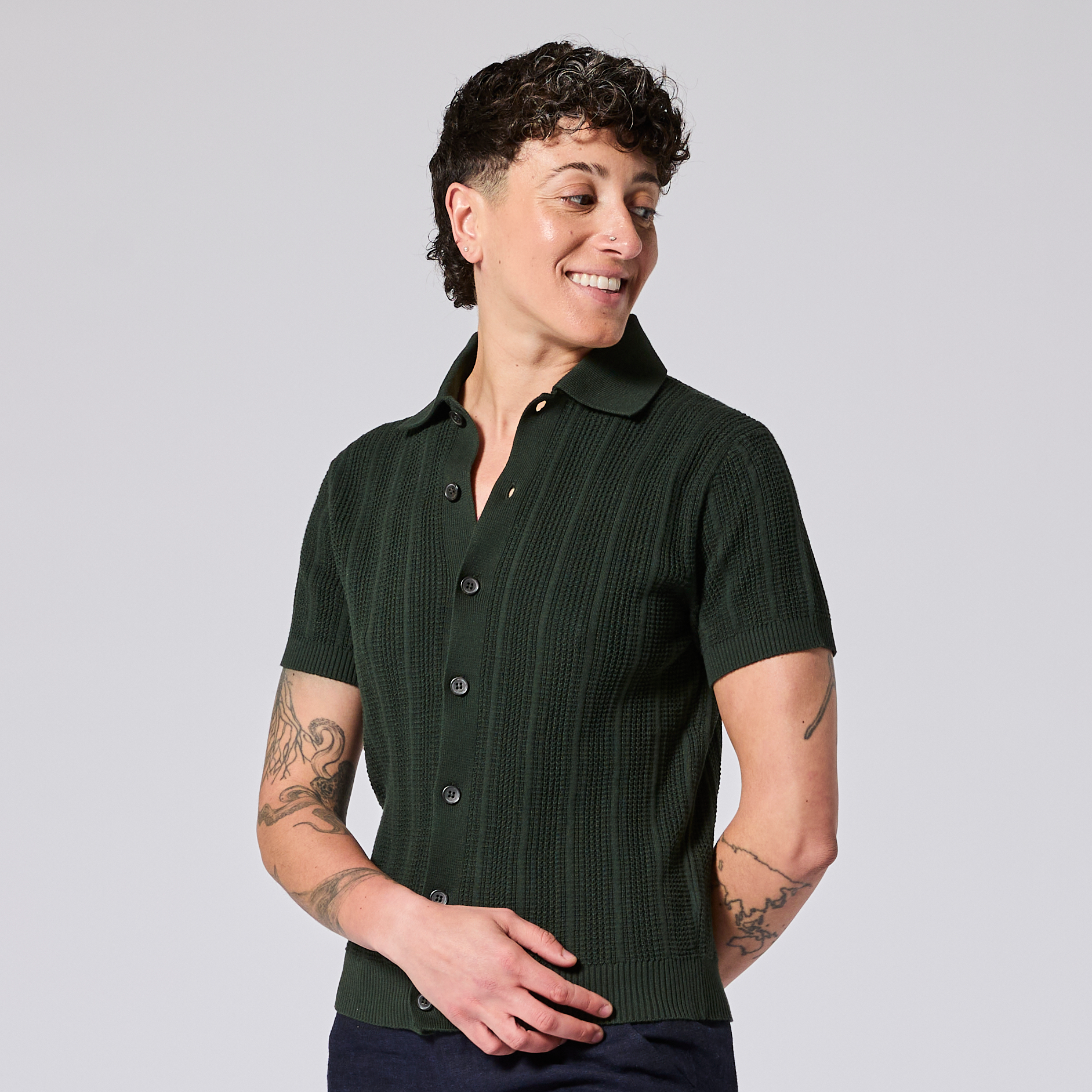 Model wearing a dark green short-sleeve cardigan on a light gray background. Color: Evergreen