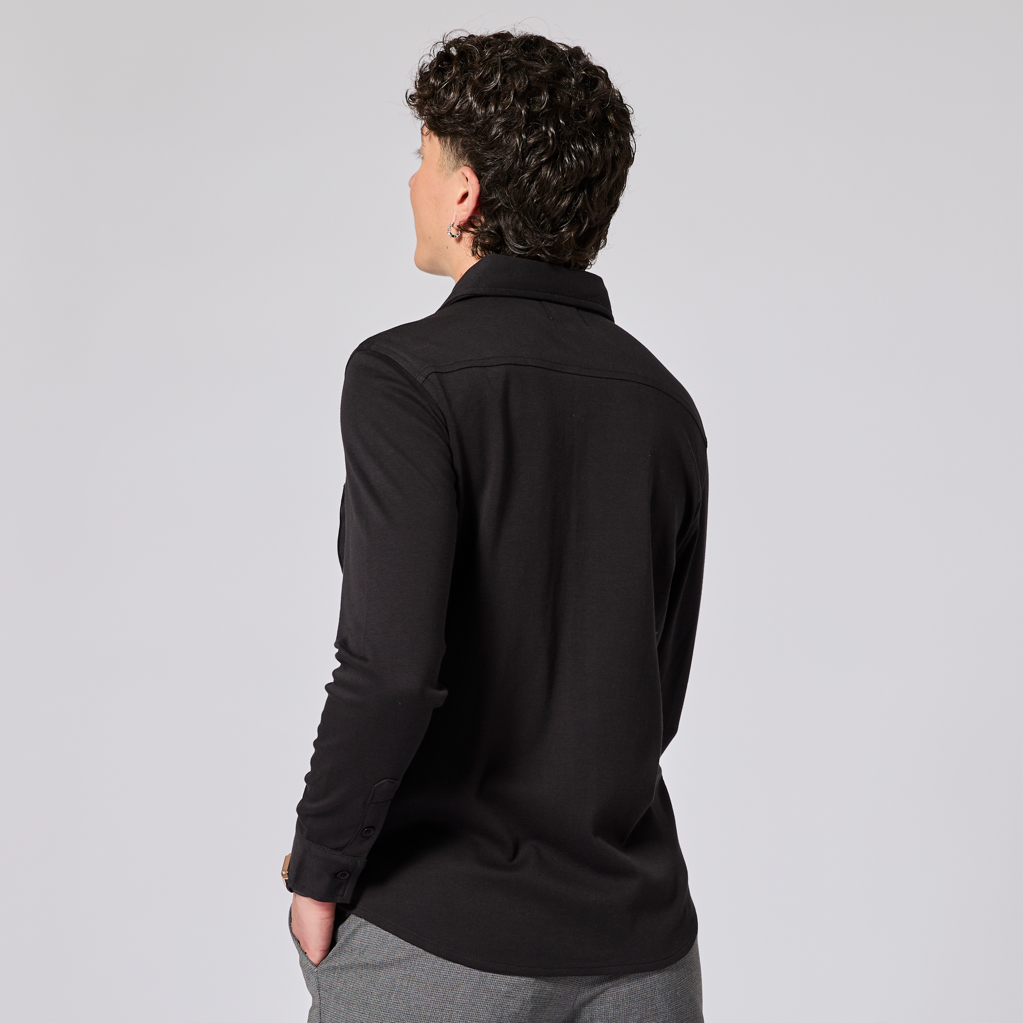 Model wearing a black dress shirt with long sleeves on a gray background. Color: Black