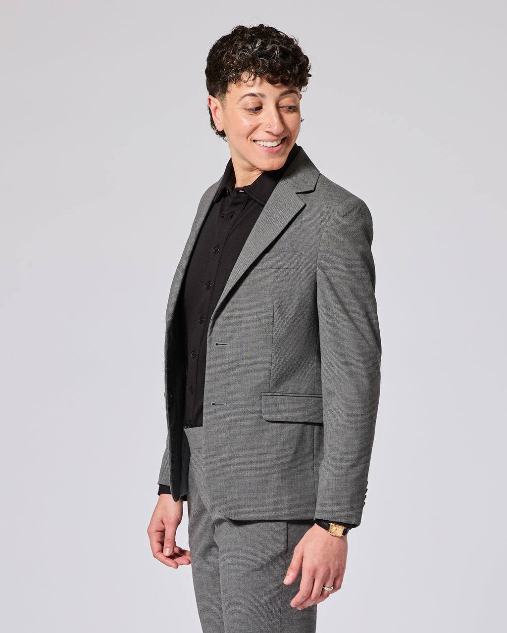 Person wearing a gray suit and black shirt on a light gray background. Color: Gray Lattice