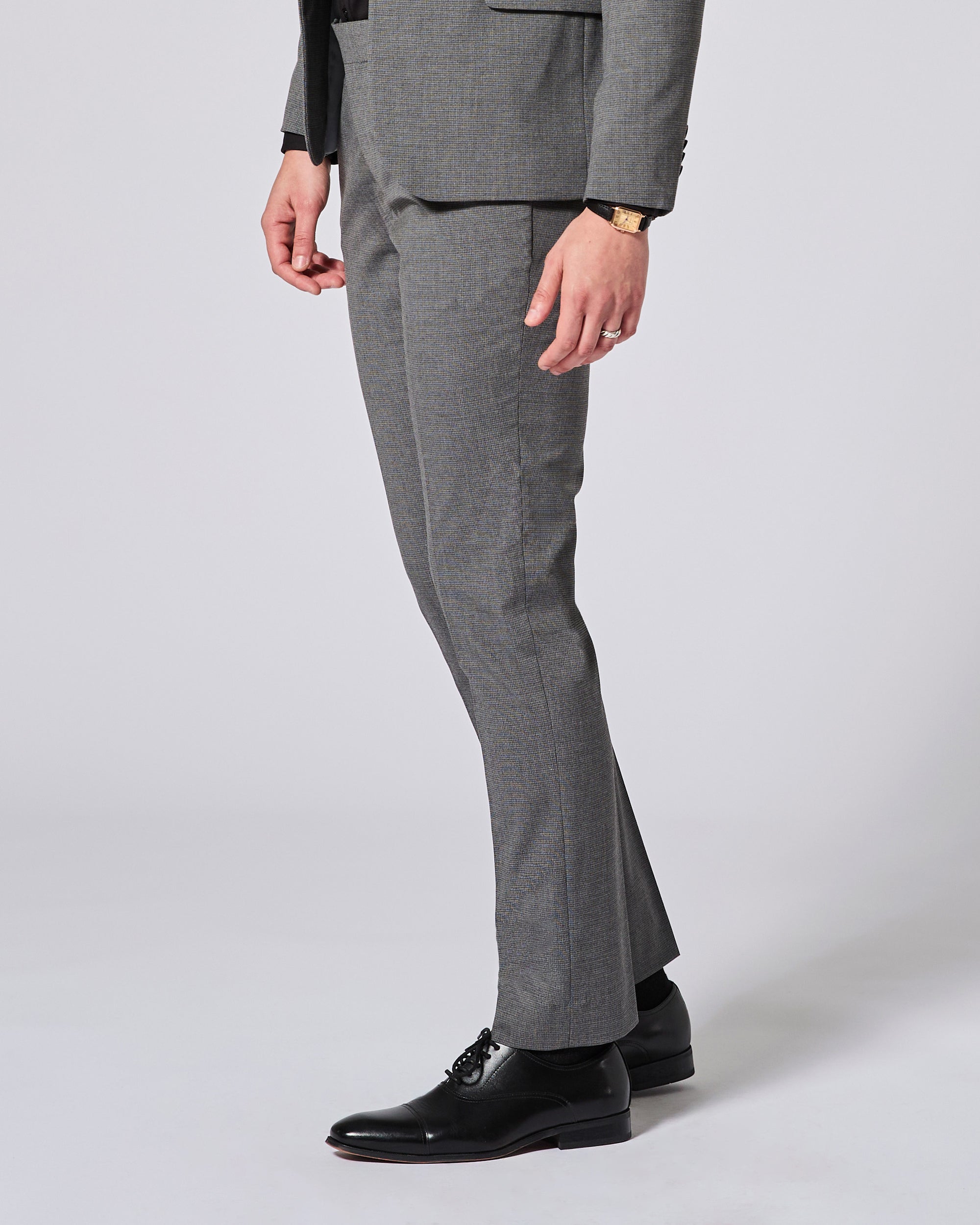 Gray suit pants worn by a person on a white background. Color: Gray Lattice