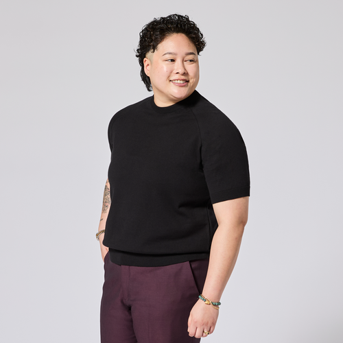 Model wearing a black raglan knit shirt and oxblood pants on a light gray background. Color: Black