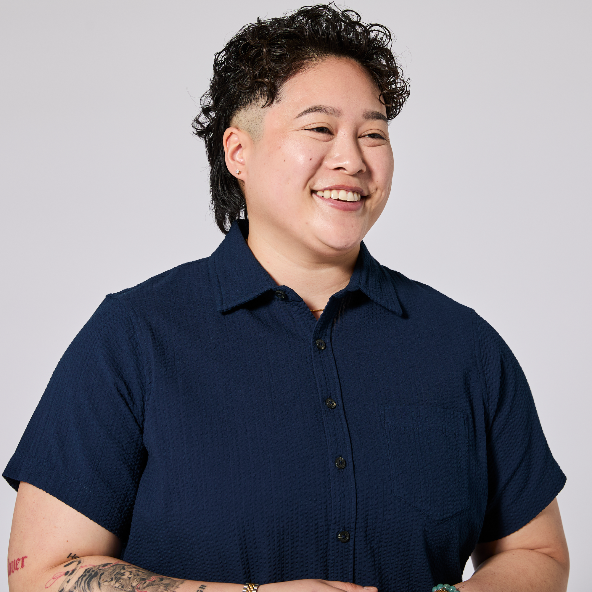 Androgynous model wearing a navy blue shirt against a plain background. Color: Azul