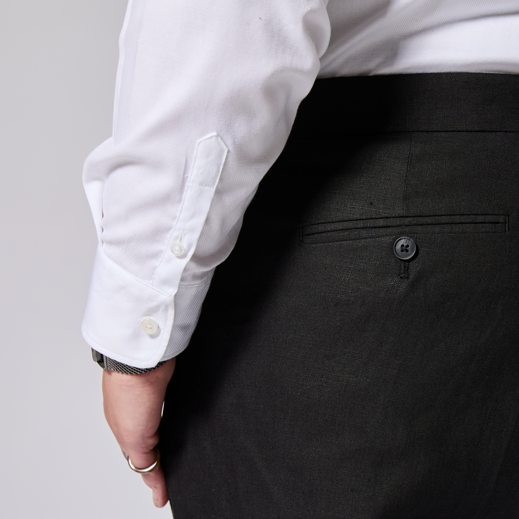 Person wearing a white shirt and black pants on a plain background. Color: Black