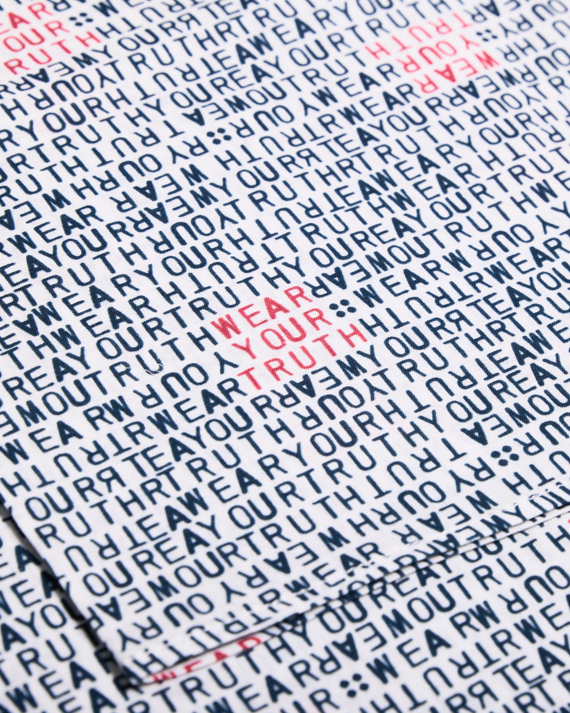 Text pattern with 'WEAR YOUR TRUTH' in red on a white bandana.