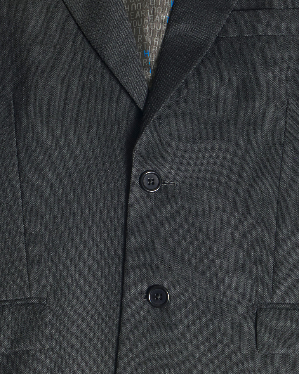 Close-up of a dark charcoal gray suit jacket with two buttons, showing the fine twill texture of the fabric and a patterned inner collar lining. Color: Nightfall Birdseye