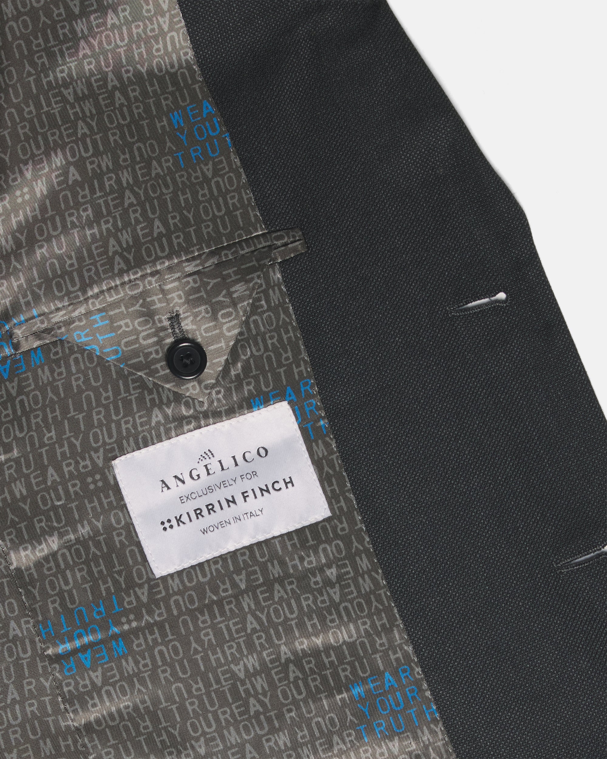 Close-up of a tailored jacket or blazer interior and side panel, showing a dark charcoal exterior and patterned gray lining. Color: Nightfall Birdseye