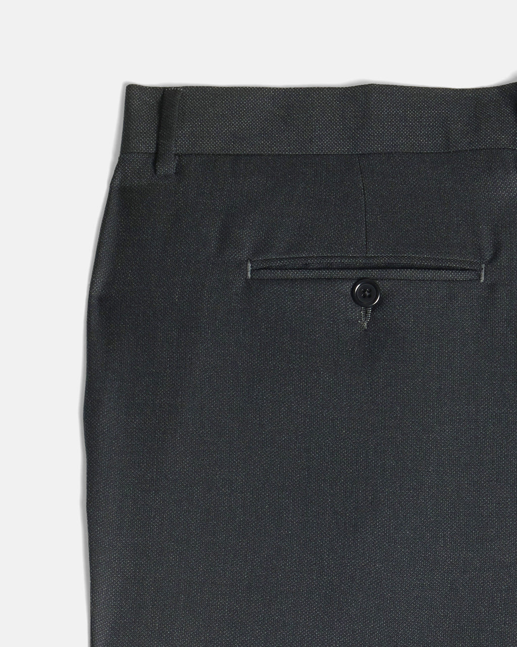 Close-up of the back waistband and rear pocket of dark charcoal gray trousers, showing a single button closure and fabric texture against a light gray background. Color: Nightfall Birdseye