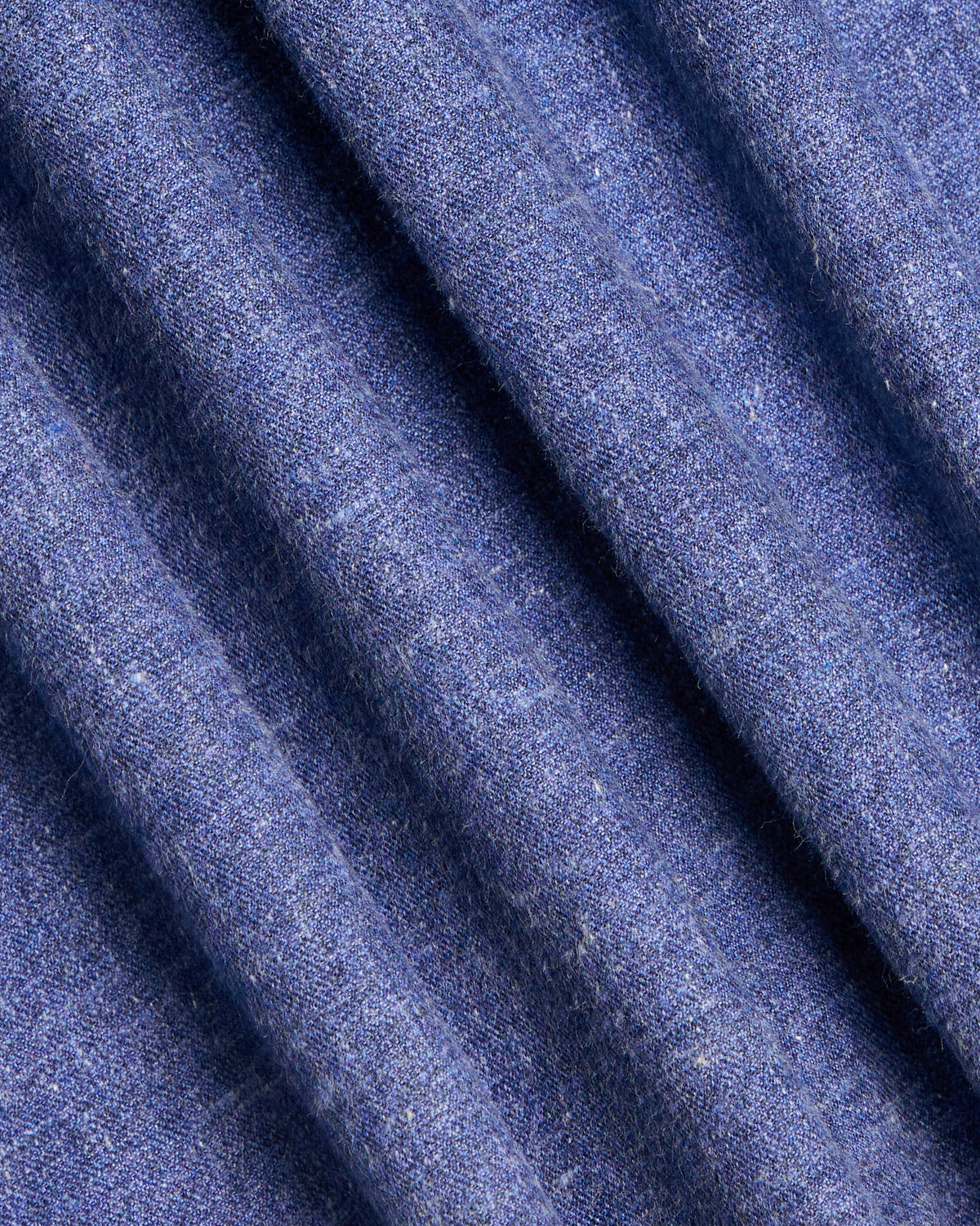 A close-up of draped blue fabric with a fine woven texture, showing soft folds and shadows. Color: Blue Marl