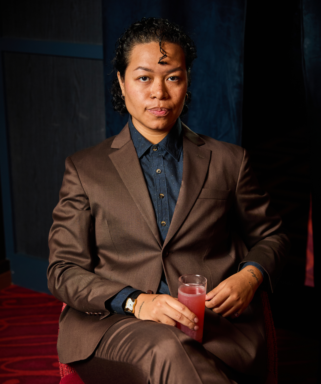 Androgynous person in The Georgie suit in Chocolate in brooding atmosphere